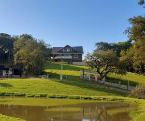 a house on a hill next to a pond at Casa da Colina Curitiba com piscina in Curitiba