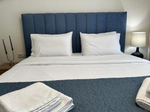 a large bed with a blue headboard and white pillows at Panorama Serenity Suites in Thessaloniki