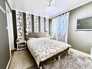 a bedroom with a bed and a curtain and a window at Arctic Getaway Sørvågen - King Crab Welcome Gift in Sørvågen