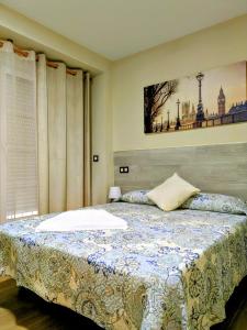 ein Schlafzimmer mit einem Bett mit einer blau-weißen Decke in der Unterkunft ALBOR II in Gijón