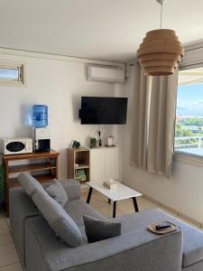 a living room with a couch and a tv at Ora Stay in Papeete