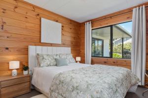 a bedroom with a white bed and wooden walls at Lockwood on Cologne in Martinborough
