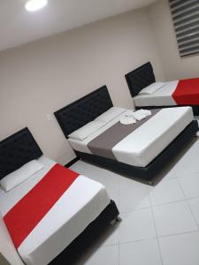 three beds in a room with red and white at Hotel Picasso 70 in Medellín