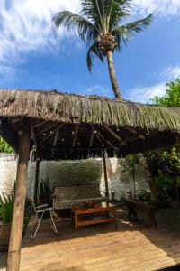 a straw hut with a bench and a palm tree at Guava Hostel Serra Grande in Uruçuca