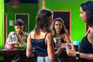 a group of women standing around a table with a green wall at Guava Hostel Serra Grande in Uruçuca +47 photos