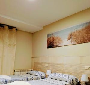 zwei Betten in einem Zimmer mit einem Bild an der Wand in der Unterkunft ALBOR II in Gijón