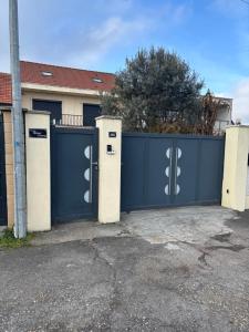 a blue fence with two gates in front of a house at Home stay Spacious room in Massy