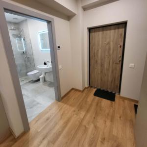 a bathroom with a toilet and a wooden door at To Be Apartament Palanga in Palanga +33 photos