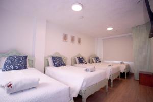 a room with three beds with white sheets and blue pillows at Hotel Cisne in Cuenca