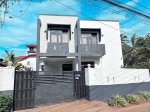 a white house with a black gate at Edelweiss Living Negombo in Negombo