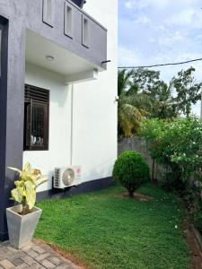 a white house with a window and a green yard at Edelweiss Living Negombo in Negombo