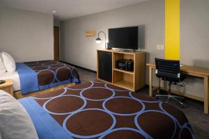 a hotel room with a bed and a desk with a television at Super 8 by Wyndham Lewiston in Lewiston