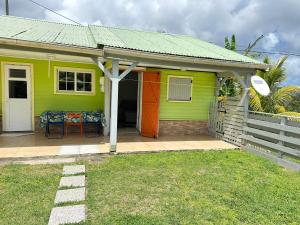 a green and orange house with a table on a porch at L'île au Vert in Gros-Morne