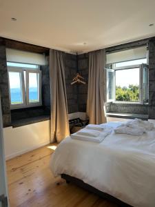 a bedroom with a large bed with two windows at Cá Por Casa Pico-Criptoméria in Prainha de Baixo