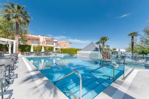 a swimming pool at a resort with chairs and palm trees at Naias in Hanioti