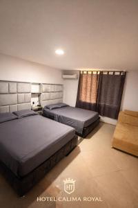a bedroom with two beds and a window at Hotel calima royal in Cali