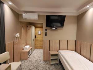 a room with a bed and a tv on the wall at Pensione Antonio - Klimatyzowane Pokoje, Centrum Słupska, Spokojny Hotel in Słupsk