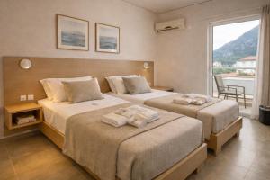 a hotel room with two beds with towels on them at Hotel Simos in Mitika