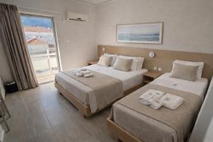 a hotel room with two beds and a window at Hotel Simos in Mitika +9 photos