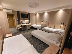 a hotel room with two beds and a desk at Pensione Antonio - Klimatyzowane Pokoje, Centrum Słupska, Spokojny Hotel in Słupsk +20 photos