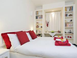 ローマにあるTermini/Colosseo Crossroad Lodgingの白いベッド1台(赤い枕、本棚付)が備わるベッドルーム1室が備わります。