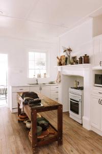 a white kitchen with a table and a stove at Ateliers Den in Beechworth