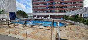 a swimming pool with chairs and a building at Quarto triplo em Petrópolis in Natal
