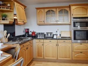 a kitchen with wooden cabinets and a stove top oven at Craigrossie Cottage in Auchterarder