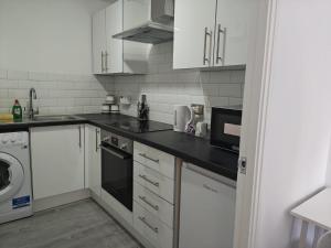 a kitchen with white cabinets and a black counter top at Thames Riverside Studio, Gravesend Town Centre - near train station in Gravesend