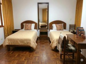 a bedroom with two beds and a table and a mirror at Hostal Chaska Inn in San Antonio