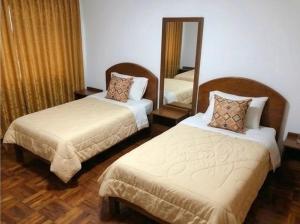 a hotel room with two beds and a mirror at Hostal Chaska Inn in San Antonio