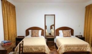 a bedroom with two beds and a mirror on the wall at Hostal Chaska Inn in San Antonio