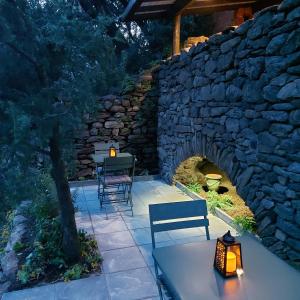 a stone wall with a table and two benches on a patio at L'abri la Vall in Sorède