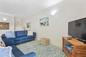 a living room with a blue couch and a tv at Baden 74 Rainbow Shores in Rainbow Beach