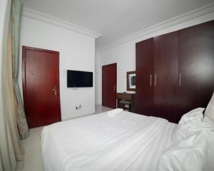 a bedroom with a white bed and wooden cabinets at AvonHeights Apartments in Lekki Phase 1