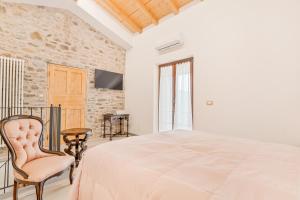 a white bedroom with a bed and a chair at La Casetta in Carafà in Aulla