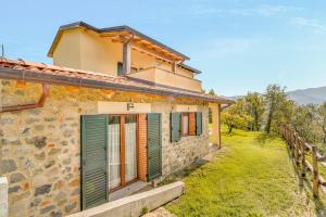 a stone house with green shutters and a fence at La Casetta in Carafà in Aulla