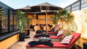 a patio with two red couches and an umbrella at Riad Sultan Suleiman & Spa in Marrakesh