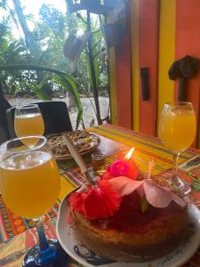 a table with a cake with a candle and glasses of orange juice at Paraisurf colombia in Nuquí