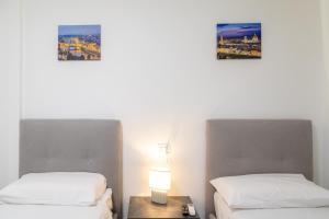 two beds in a room with a table and a lamp at Sara Home Flo in Florence