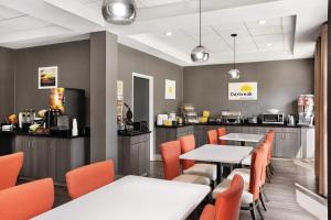 a dining room with tables and orange chairs at Days Inn & Suites by Wyndham Murfreesboro I-24 East in Murfreesboro