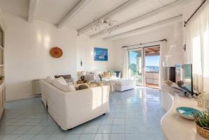 a living room with white furniture and a large window at Villa Emmeline fronte mare 5 camere 6 bagni infinity pool WiFi per 12 persone in Alghero