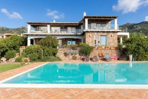 a villa with a swimming pool in front of a house at Villa Emmeline fronte mare 5 camere 6 bagni infinity pool WiFi per 12 persone in Alghero