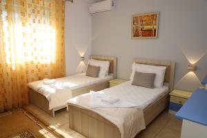 two beds in a small room with two lamps at Lana's House in Berat