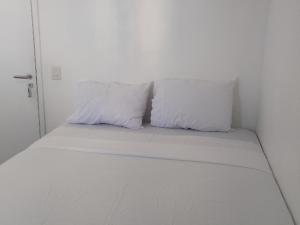 two white pillows sitting on a bed in a room at Quartos - Cíntia in Fortaleza