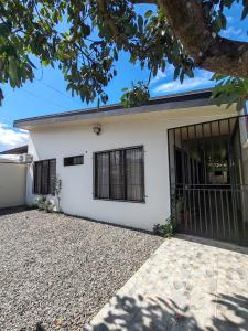 a white house with black windows and a driveway at Butterfly Apartments La Fortuna in Fortuna