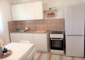 a small kitchen with white cabinets and a refrigerator at Apartment Roko in Podstražje +14 photos