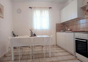 a kitchen with a table and chairs and a window at Apartment Roko in Podstražje
