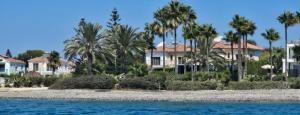 a row of houses on the beach with palm trees at 7 Bdr Villa with Heated Pool & Spa in Mazotos