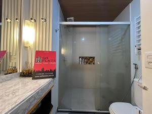 a bathroom with a shower and a toilet with a sign at Flat de Luxo no Quality Hotel no coração de Alphaville in Barueri +21 photos